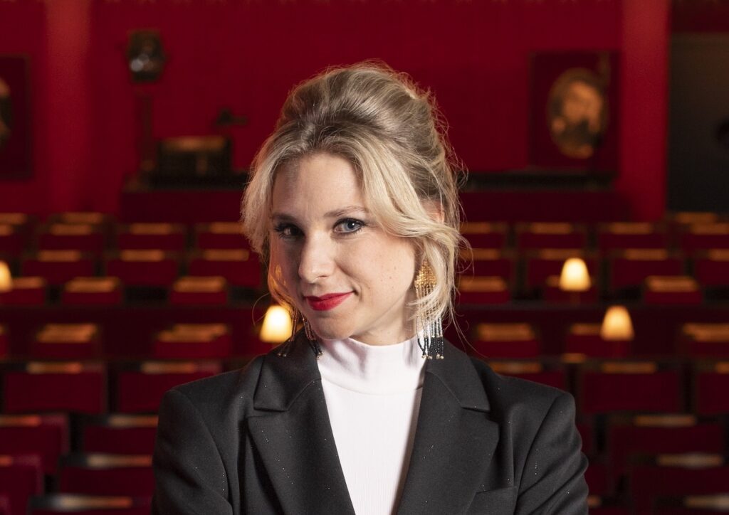 Porträt von Jenny Frankl im dunkelroten Zuschauerraum des Kabarett Simpl 